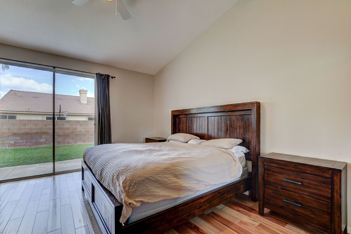 Master bed with vaulted ceiling, ceiling fan and oversized sliding glass doors